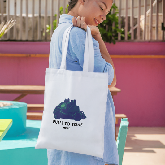 Person holding a tote bag with a graphic design in an outdoor setting